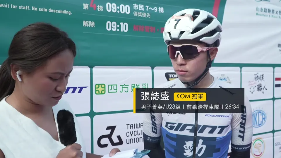 主持人在背板前訪問 KOM 冠軍選手。