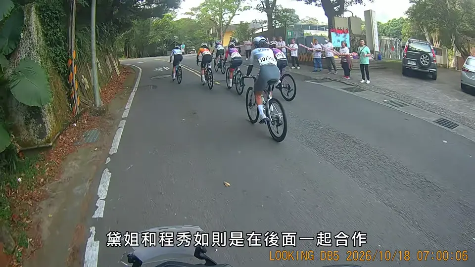 女子選手沿彎道上坡，後方跟著一小群騎士。